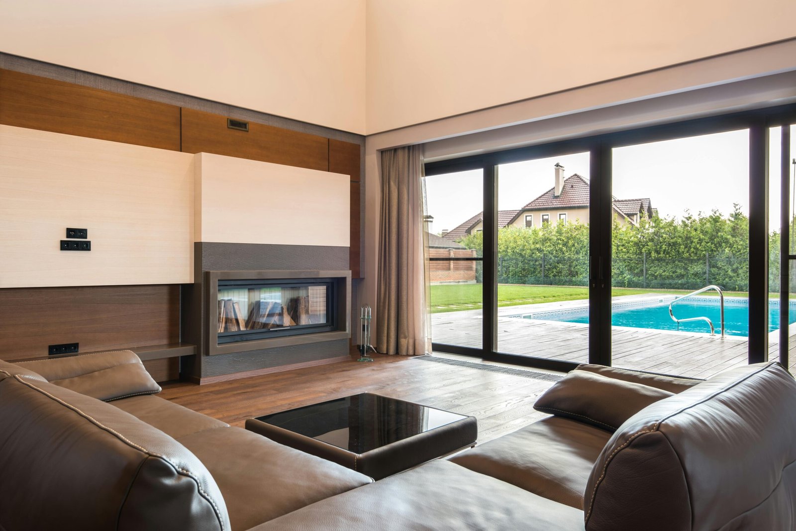 Spacious modern living room with glass doors opening to a poolside area.
